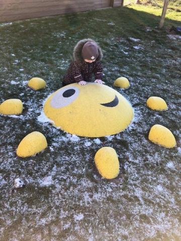 Et billede af et barn der kravler på en sol på legepladsen